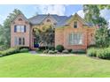 Elegant brick home featuring manicured lawn, mature trees, and a welcoming entrance at 2118 Town Manor Ct, Dacula, GA 30019