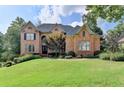 Elegant brick home featuring manicured lawn, mature trees, and a welcoming entrance at 2118 Town Manor Ct, Dacula, GA 30019