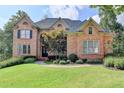 Elegant brick home featuring manicured lawn, mature trees, and a welcoming entrance at 2118 Town Manor Ct, Dacula, GA 30019