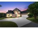 Stately brick home at dusk with a circular driveway, lush lawn, mature landscaping, and a three-car garage at 9325 Saint Georgen Cmn, Duluth, GA 30097
