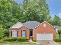 A brick home featuring an attached two-car garage, manicured shrubs, and a well-maintained lawn at 361 Brackin Trce, Grayson, GA 30017