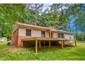 Ranch-style home featuring a red roof, brick foundation, and a wooden deck overlooking the backyard at 428 Cornish Mountain Rd, Oxford, GA 30054