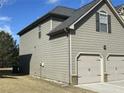 A view of the side of a two-story home with neutral color siding and an attached two-car garage at 1291 Long Acre Dr, Loganville, GA 30052