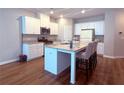 Bright kitchen with stainless appliances, granite counters, white cabinets, and seating at the island at 2059 Lanier Harbor Pt, Buford, GA 30518