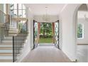 Elegant foyer showcasing an open staircase, modern chandelier, and black steel double front doors at 6428 East Cherokee Dr, Canton, GA 30115