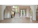 Spacious foyer featuring an open staircase, black steel doors, light wood flooring, and arched doorways at 6428 East Cherokee Dr, Canton, GA 30115