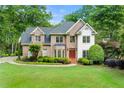 Brick facade home with red doors, manicured lawn and mature trees create a welcoming curb appeal at 125 Forrest Lake Rd, Johns Creek, GA 30022