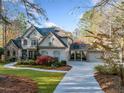 Traditional home with attached and detached garages, beautifully landscaped yard, and mature trees at 8170 Hurakan Creek Xing, Cumming, GA 30028