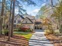 Traditional two-story home showcasing a manicured front lawn, a porte-cochere, and mature trees at 8170 Hurakan Creek Xing, Cumming, GA 30028