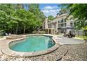 A luxurious backyard pool features a spa, a stone patio, and seating areas for relaxation at 8170 Hurakan Creek Xing, Cumming, GA 30028