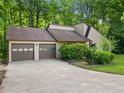 Charming home featuring a two-car garage and driveway surrounded by mature trees and landscaping at 162 Riverchase Dr, Woodstock, GA 30188