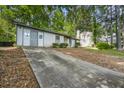 A single-story home with light siding, a stone accent, and a long concrete driveway at 5445 Mallard Trl, Lithonia, GA 30058