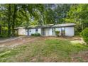 A single-story home with light siding, a stone accent, and a long driveway at 5445 Mallard Trl, Lithonia, GA 30058