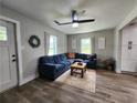 Inviting living room features a comfortable, blue sectional sofa, modern ceiling fan, and bright natural light at 6567 Post Rd, Douglasville, GA 30135