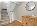 Hallway featuring a staircase, hardwood floors, decorative cabinet, and a stylish round mirror at 701 Dunwoody Chace, Atlanta, GA 30328