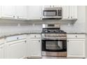 Kitchen displays white cabinetry, granite countertops, and stainless steel appliances at 5335 Lexington View Pl, Sugar Hill, GA 30518