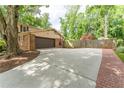 Spacious driveway leading to a two-car garage and a home with brick accents and mature trees at 1652 Weymouth Ct, Tucker, GA 30084