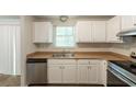 Well-lit kitchen featuring white cabinets, stainless steel dishwasher, and wood look flooring at 5372 Martins Crossing Rd, Stone Mountain, GA 30088