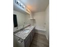 Bathroom featuring double sinks with granite counters, wood look floors and tub with shower at 1700 Devon Sw Dr, Atlanta, GA 30311