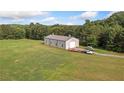 Large metal outbuilding on vast green lawn with surrounding woods at 829 Christopher Rd, Sharpsburg, GA 30277