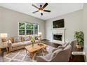 Cozy living room featuring a fireplace, ceiling fan, and large window overlooking the backyard at 617 Kyles Cir, Hiram, GA 30141