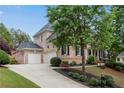 Two-story brick home featuring an attached three-car garage and meticulously landscaped yard at 2020 Windermere Xing, Cumming, GA 30041