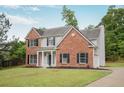 Angle view of a home featuring a combination of brick and siding, complemented by black shutters and a well-maintained lawn at 463 The Gables Dr, Mcdonough, GA 30253