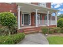 Inviting front porch with brick steps, white columns, and a decorative front door at 3305 Millwater Xing, Dacula, GA 30019