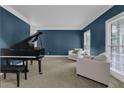 Cozy living room features blue walls, a grand piano, and two comfortable armchairs at 3305 Millwater Xing, Dacula, GA 30019