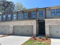 Stylish townhome showing the brick front, two-car garage, landscaping, and neutral exterior colors at 1406 Lucan Nw Ln # Wc221, Lawrenceville, GA 30043