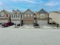 View of townhomes featuring two-car garages, attractive architectural details, and well-maintained landscaping at 3318 Sardis Bend Dr, Buford, GA 30519