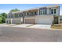 Row of modern townhomes with brick and siding exteriors, each featuring a two-car garage and landscaped front yards at 2335 Portrush Way (Lot 26) Dr, Atlanta, GA 30339