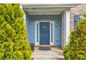 Classic blue front door framed by lush greenery and brick accents, creating a welcoming entrance at 133 Parkway Dr, Fairburn, GA 30213