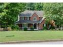 Lovely brick home with a covered front porch and lush green lawn, surrounded by mature trees at 2995 Aspen Ridge Ct, Snellville, GA 30078