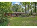 Traditional-style home featuring a brick facade, red shutters, and a green lawn, nestled among mature trees at 1981 Bramblewood Ne Dr, Brookhaven, GA 30329