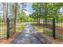View of gated driveway leading to a home surrounded by trees, offering privacy and curb appeal at 218 Ward Rd, Ellenwood, GA 30294