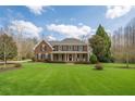 Inviting brick home featuring a large lawn, covered porch, and classic architectural details at 210 Little River Farms Trl, Canton, GA 30115