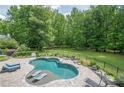 Inviting backyard pool with sun loungers, lush landscaping, and a serene wooded backdrop at 210 Little River Farms Trl, Canton, GA 30115