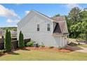 Side view of a light gray home featuring a two-car garage, manicured lawn, and privacy fence at 501 White Oak Path, Canton, GA 30115