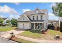 Well-maintained home featuring a two-car garage, a front porch with rocking chairs, and an expansive green lawn at 501 White Oak Path, Canton, GA 30115