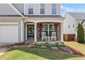 Close-up of the front porch with stone accents, white rocking chairs, and decorative floral arrangements at 501 White Oak Path, Canton, GA 30115