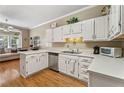 Well-lit kitchen featuring white cabinetry, stainless steel dishwasher, and hardwood floors at 1201 Bridle Path, Marietta, GA 30068