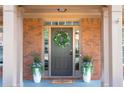 Close-up of a home's entryway showcasing decorative wreath, potted plants, and welcome mat at 5281 Tormeall Trce, Suwanee, GA 30024
