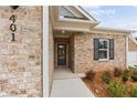 Inviting home entrance with brick facade, manicured landscaping, and modern black front door at 401 Village Ln, Fairburn, GA 30213