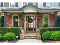 Inviting front porch with stone pillars, a decorative wreath, and manicured hedges, creating a welcoming entrance at 5025 Savannah Run, Cumming, GA 30040