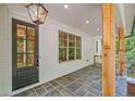 Inviting front porch featuring stone flooring, wooden pillars, and a stylish glass-paneled door at 2585 Hickory Rd, Canton, GA 30115