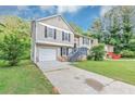 Exterior view of home featuring attached garage, neutral siding and large driveway at 5290 Forest Downs Ln, Atlanta, GA 30349