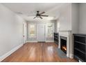 Inviting living room featuring hardwood floors, a cozy fireplace, ceiling fan, and natural light from the windows at 763 Jones Nw Ave, Atlanta, GA 30314