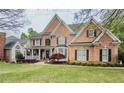 A beautiful two-story brick home with a lush green lawn and mature trees in a suburban setting at 710 Bentgrass Ct, Dacula, GA 30019