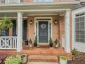 Inviting front porch with brick flooring, elegant lanterns, and a charming monogrammed wreath at 710 Bentgrass Ct, Dacula, GA 30019